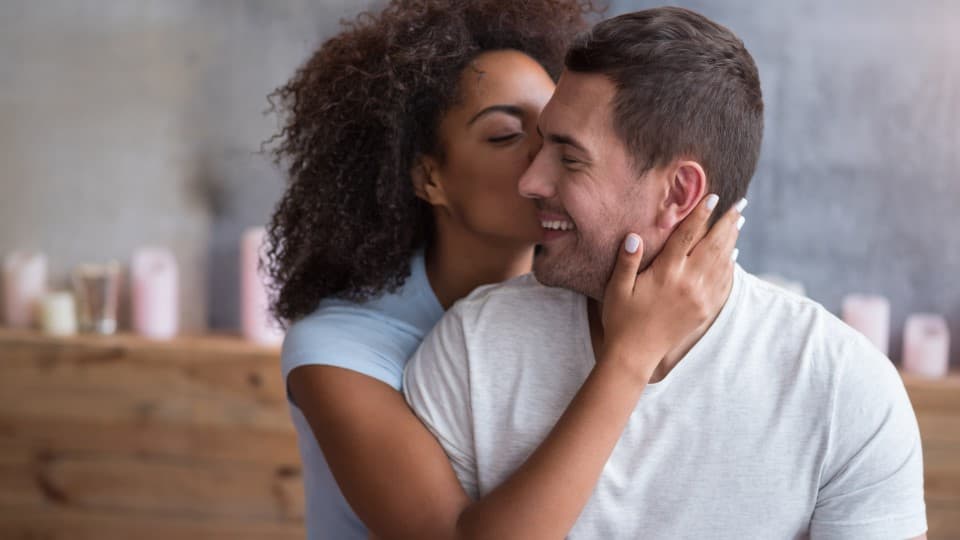 A woman kisses a man on the cheek